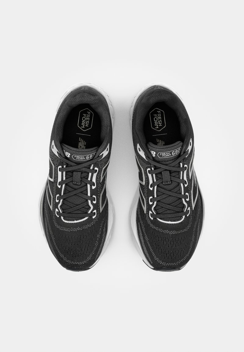 Zapatillas deportivas negras con parte superior de malla, acentos blancos, diseño texturizado y suela acolchada. Presenta cordones y logo en la lengüeta.
