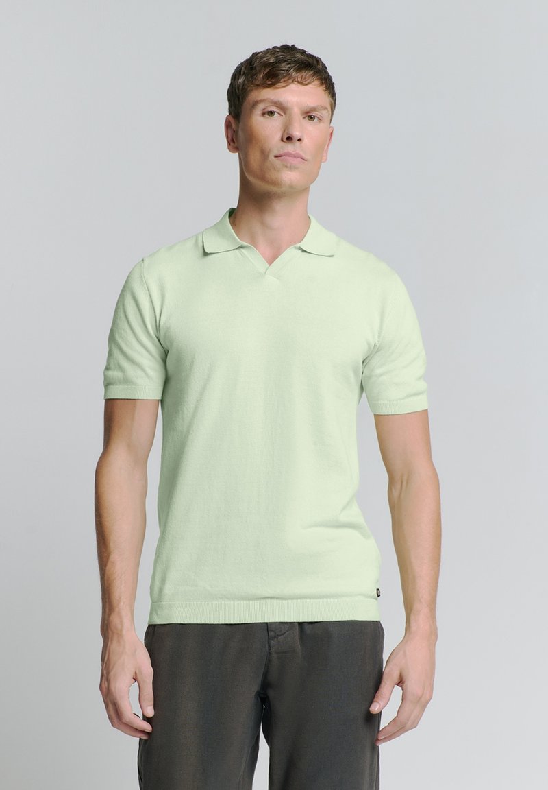 Lichtgroen gebreid poloshirt met een V-hals, korte mouwen en een aansluitend ontwerp. Heeft een geribbelde zoom en een subtiele logo-accent nabij de onderkant.