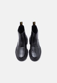 Μαύρα γυαλιστερά δερμάτινα μποτάκια πλατφόρμας με φερμουάρ μπροστά και επώνυμα τριχιά τράβηγμα, απεικονιζόμενα από πάνω σε λευκό φόντο.