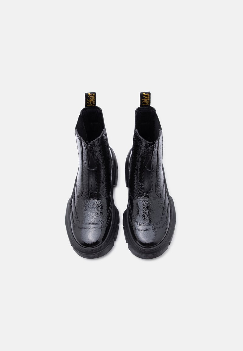 Zwarte glanzende leren plateau enkellaarsjes met ritssluitingen aan de voorkant en merkaccenten aan de trekbanden, gezien van bovenaf op een witte achtergrond.