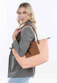 Borsa tote in morbido materiale rosa con dettagli in pelle marrone. Presenta una tasca con zip sul davanti e manici resistenti. Finitura testurizzata.