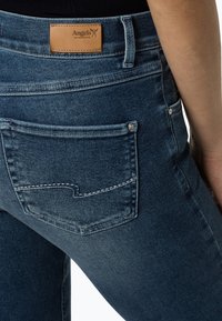 I jeans in denim blu scuro presentano un'etichetta in pelle sulla vita e un design distintivo della tasca posteriore con cuciture a contrasto.