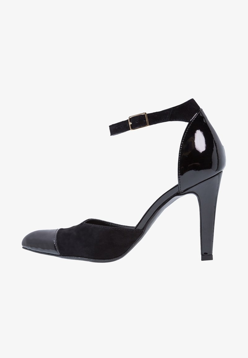 Chaussure à talons hauts noire pour femme avec bout pointu, bride à la cheville avec boucle dorée et combinaison de matériaux en daim et cuir verni.