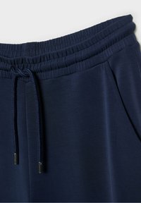Marineblauwe joggerbroeken met een elastische tailleband, verstelbare trekkoordsluiting en zijzakken, met een vloeiende, zachte textuur.