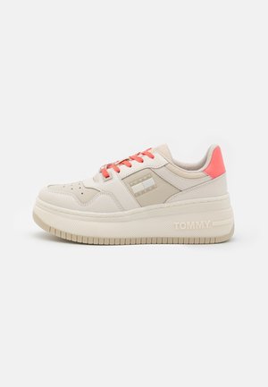 Masywny beżowy sneaker z koralowymi sznurówkami i pętelką na pięcie, perforowany czubek, oznaczony boczny panel oraz gruba podeszwa z napisem "TOMMY".