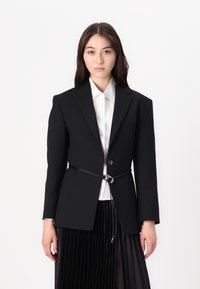 Black tailored blazer featuring a single button closure, a belted waist with metallic hardware, and sharp lapels over a white shirt.