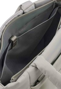 Interno della borsa grigia chiara con tessuto liscio, dotato di un vano con zip e numerosi scomparti aperti per l'organizzazione.