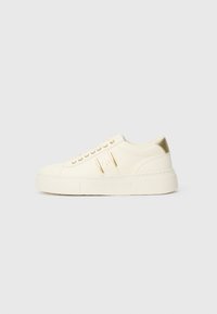 Krem-beige niske tenisice s zlatnim detaljima, vezicama i utisnutim "Armani Exchange" brendom na potplatu i bočnoj oznaci.