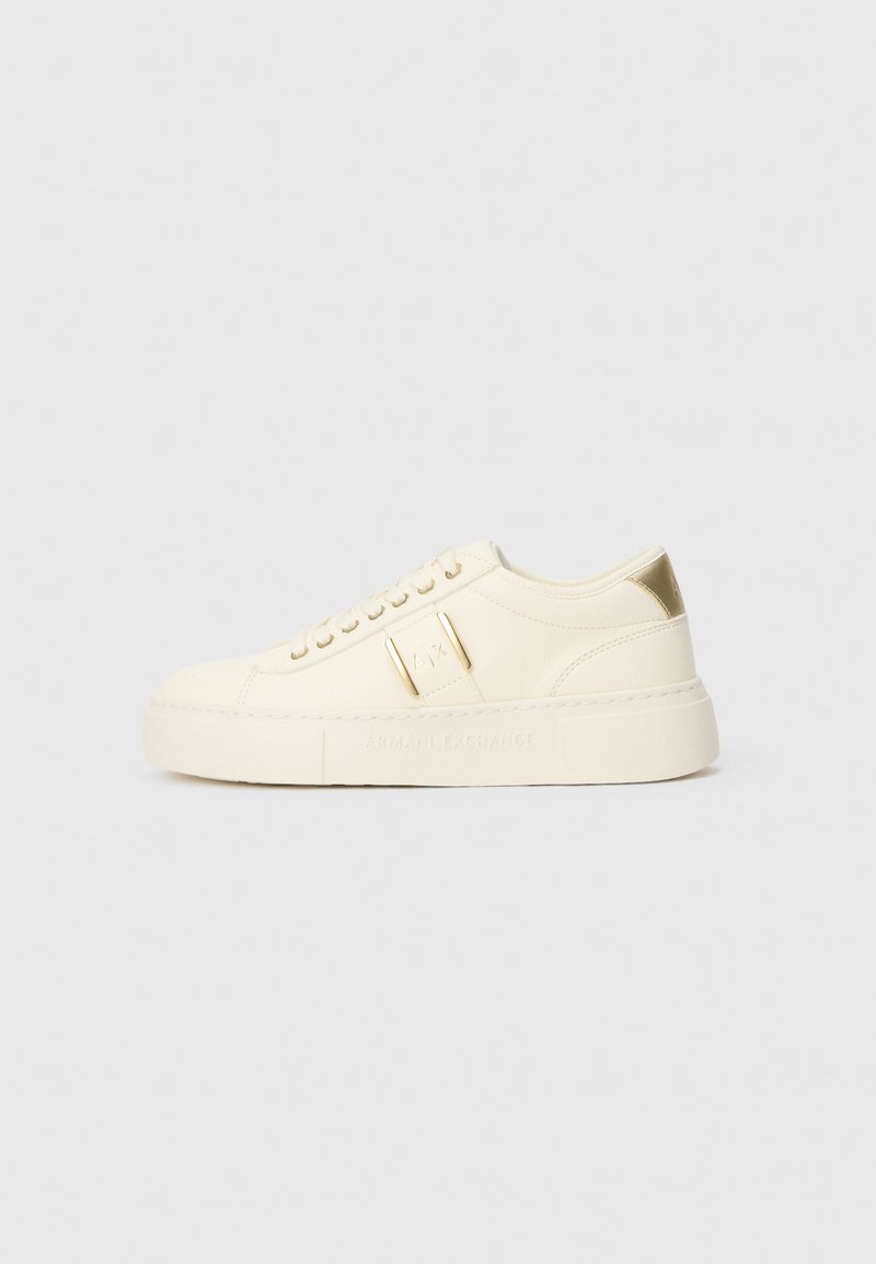 Krem-beige niske tenisice s zlatnim detaljima, vezicama i utisnutim "Armani Exchange" brendom na potplatu i bočnoj oznaci.