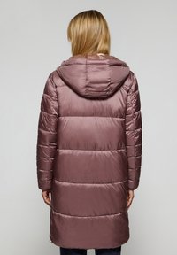 Cappotto lungo imbottito di colore rosa tenue, con sezioni trapuntate orizzontali, cappuccio e una texture liscia e lucida.