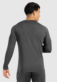 Langarm-Sportshirt in Dunkelgrau, aus glattem, dehnbarem Material gefertigt. Verfügt über Raglanärmel und einen einfachen Rundhalsausschnitt.