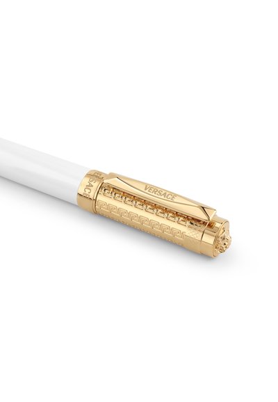 Stylo blanc avec un capuchon doré orné présentant un motif clé grec gravé, le logo Versace et un emblème de tête de Méduse à l'extrémité du clip.