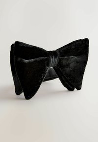 Schwarze Samtfliege mit strukturiertem Oberflächen, auffälliger Form mit breiten Flügeln und einem zentralen Knoten zum Verschließen.