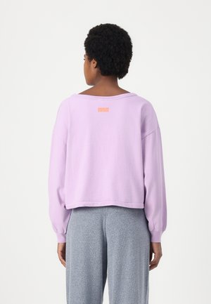 Lavendel cropped sweatshirt met een relaxte pasvorm en lange mouwen. Heeft een oranje "American Vintage" logo op de achterkant. Gladde textuur.