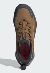 Brown hiking shoe with a textured upper, mesh accents, and black rubber sole. Features a Goodyear logo and reinforced toe cap for durability.