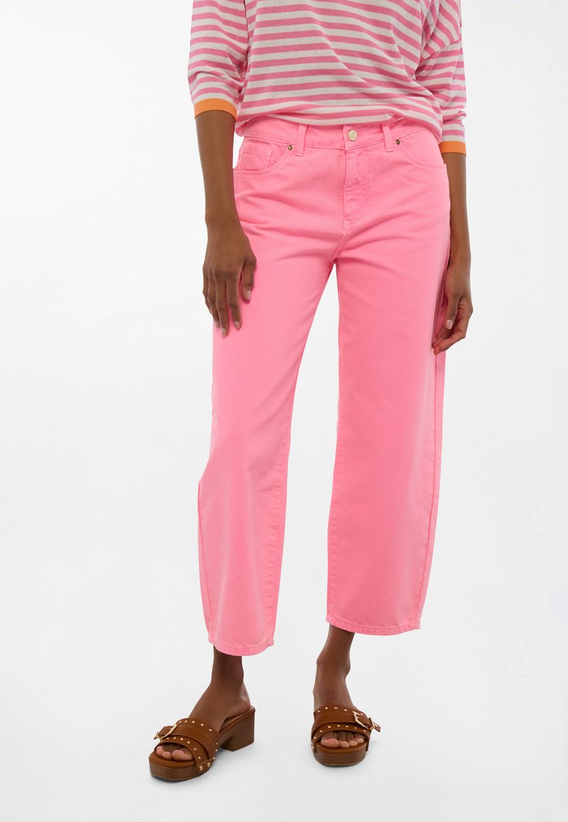 Ružové nohavice s širokými nohavicami vyrobené z bavlny, s klasickým päťvreckovým dizajnom a zapínaním na gombík. Kombinované s hnedými platformovými sandálmi.