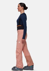 Roze skibroek met zwarte accenten en een oranje rits, voorzien van verstelbare banden, zijzakken en versterkte knieën.