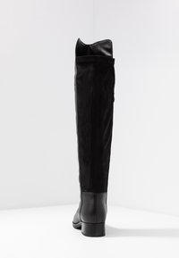 Botas negras hasta la rodilla que combinan cuero liso y ante, con un tacón apilado y un borde superior ligeramente doblado.