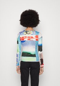 Dlouhý rukáv, přiléhavé tričko s barevným abstraktním potiskem, obsahující různé vzory v modré, zelené, červené a černé barvě na bílém podkladu.