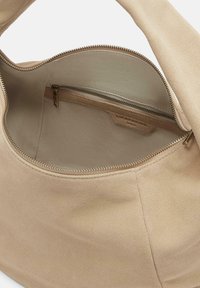 Sac en daim beige à la texture douce. Il dispose d'une fermeture éclair et d'une petite poche intérieure. La doublure lisse complète le design global.