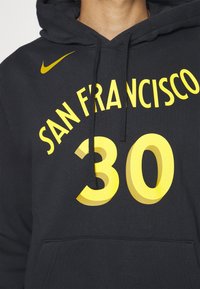 Hoodie noir avec le texte "San Francisco" en jaune courbé au-dessus d'un grand num éro 30 et un swoosh jaune de Nike sur la poitrine.