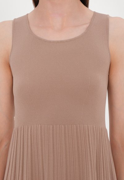 Tank-dress valkoisessa pehmeässä ribbikangassa, jossa on tiukka yläosa ja laskostettu hame, sileä pääntie eikä näkyviä kiinnikkeitä.