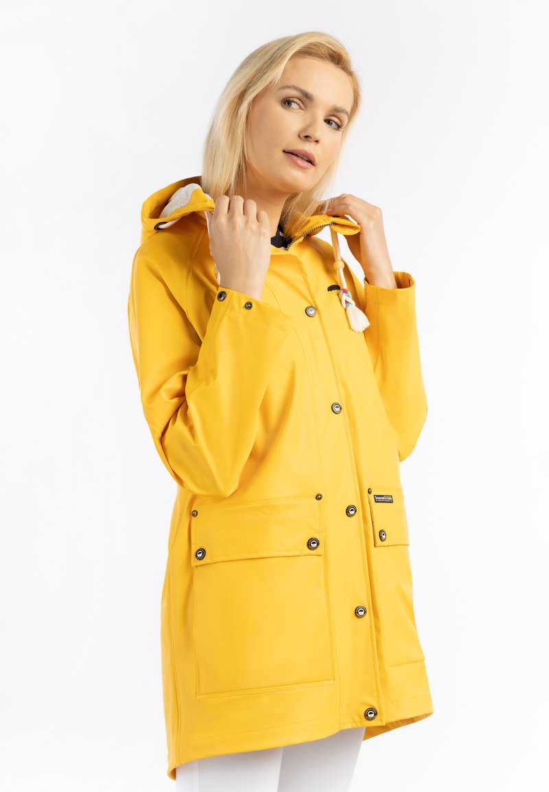 Impermeable amarillo con capucha desmontable, botones a presión y dos bolsillos frontales. Presenta un acabado texturizado y cordones de colores.
