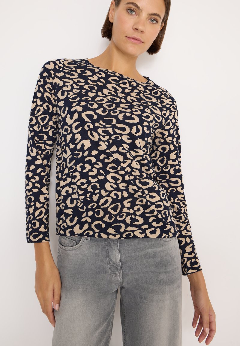Maglietta a maniche lunghe di colore navy con stampa leopardata beige, scollo rotondo, tessuto morbido e vestibilità comoda, abbinata a jeans grigi chiari.