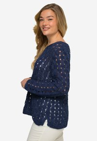 Marineblau gehäkelter Pullover mit offener Maschenstruktur, langen Ärmeln und abgerundetem Saum. Das Material zeigt eine ausgeprägte Textur und Muster.