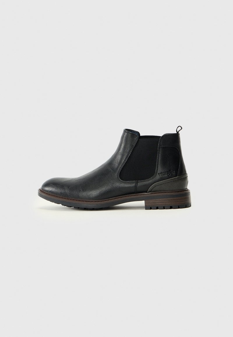 Bottes Chelsea en cuir noir avec panneaux élastiques sur les côtés, bout rond et talon bas empilé. Dispose d'une languette à l'arrière pour un enfilage facile.