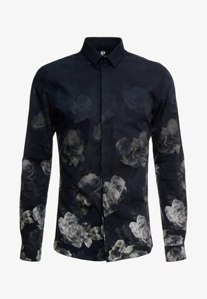 Chemise à boutons en tissu bleu marine avec de grands imprimés floraux gris. Dotée d'un col classique et de manches longues avec des poignets boutonnés.