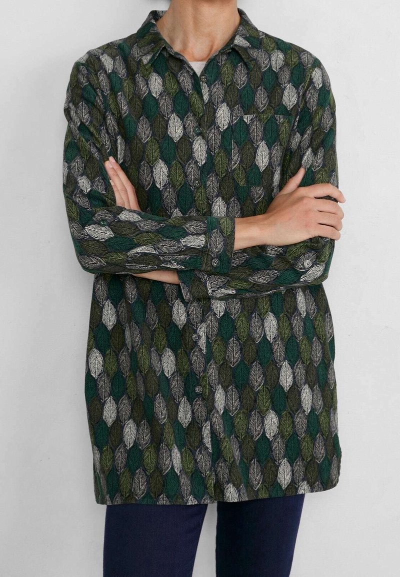 Camicia con maniche lunghe e bottoni, caratterizzata da un motivo a foglie verde, nero e bianco. Il tessuto ha una consistenza tattilmente interessante. Presenta un colletto e polsini.