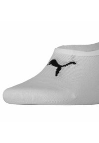 Białe skarpetki typu no-show z czarnym logo Puma na górze z przodu, wykonane z materiału przypominającego siatkę.