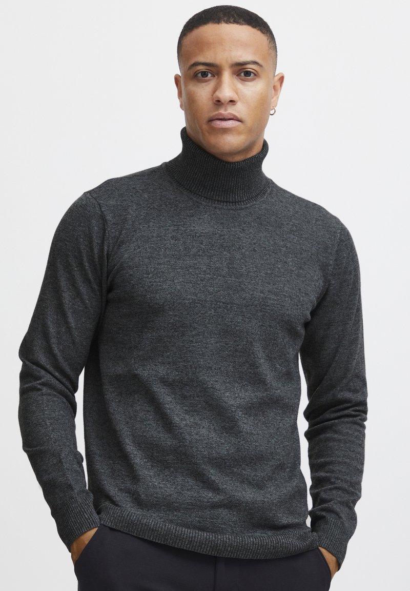 Suéter de cuello alto en gris oscuro, hecho de un tejido suave y texturizado. Presenta mangas largas y un cuello y dobladillo acanalados.