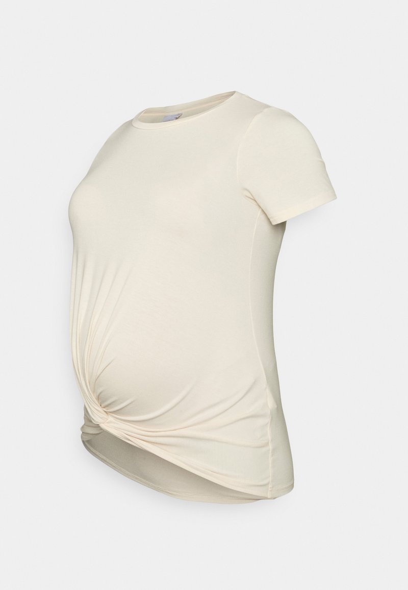 T-shirt de maternidade em creme claro, feito em tecido macio. Apresenta um detalhe de nó torcido na cintura e uma gola arredondada. Mangas curtas.