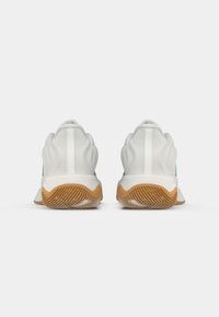 Witte sportieve schoenen met een gestructureerd ontwerp, voorzien van een rubberen zool, ronde vormen en een bovenwerk van zacht materiaal. Heeft een gebogen achterdetail.