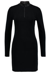 Robe noire à manches longues avec un col montant et une demi-fermeture éclair ; fabriquée dans un tissu lisse avec une texture côtelée et un détail de col marqué.