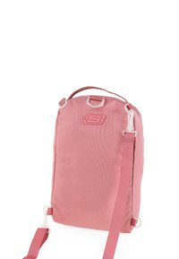 Mochila de tela rosa con una textura suave, que cuenta con un asa superior, correa ajustable y un logotipo en la parte frontal. Incluye detalles de hardware de plástico.