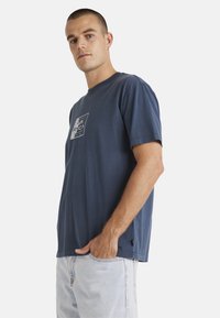 Navy blue cotton t-shirt with short sleeves, crew neck, and a graphic logo on the chest. Casual fit with visible stitching details.