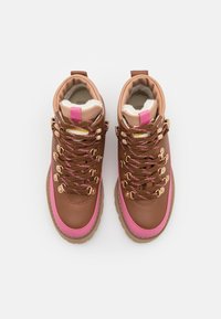 Brune lædervandrestøvler med pink detaljer, polstret krave og metaløjer. Har strukturerede snørebånd og en gummisål.