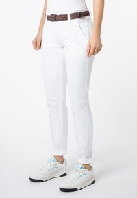 Witte skinny jeans met een hoge taille, voorzien van voorzakken en omgerolde broekspijpen. Gepaarde met witte sneakers met pasteltinten en gestructureerde veters.