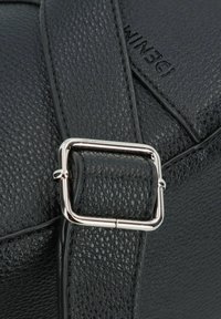 Bolso de cuero texturizado negro con una hebilla cuadrada plateada en la correa, con branding en relieve y un acabado suave en los bordes.