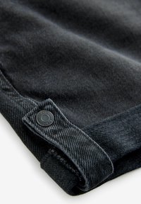 Dunkelgrauer Denimstoff mit strukturiertem Finish, ausgestattet mit einem metallischen Knopfdetail und einer genähten Saumkante am Ärmel.