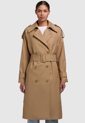 Beige trench coat with double-breasted button closure, wide collar, belted waist, and shoulder epaulets; fabric is smooth with a structured design.