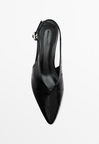 Černá kožená slingback obuv s špičatou špičkou a texturovaným povrchem. Obsahuje stříbrnou sponu a otevřené strany pro prodyšnost.