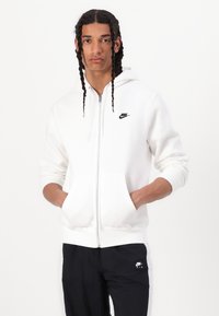 Λευκό φούτερ με φερμουάρ και κουκούλα, εμπρόσθιες τσέπες και μαύρο λογότυπο Nike στο αριστερό μέρος του στήθους. Διαθέτει ριμπ μανσέτες και λεία υφή.