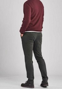 Pantalon de survêtement gris foncé à coupe slim, taille élastique et poches latérales, associé à un pull torsadé texturé couleur bordeaux.