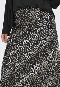 Flerfarget leopardmønstret skjørt i svart, brunt og hvitt. Har en flytende design og glatt tekstur med en tettsittende midjebånd.
