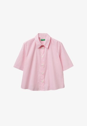 Camisa rosa de manga corta con pequeños puntos rojos, un cuello puntiagudo y una etiqueta verde dentro del cuello.