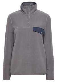 Pullover in pile grigio con colletto alto, tre bottoni a pressione sul collo e una tasca a toppa blu a contrasto sulla parte sinistra del petto.